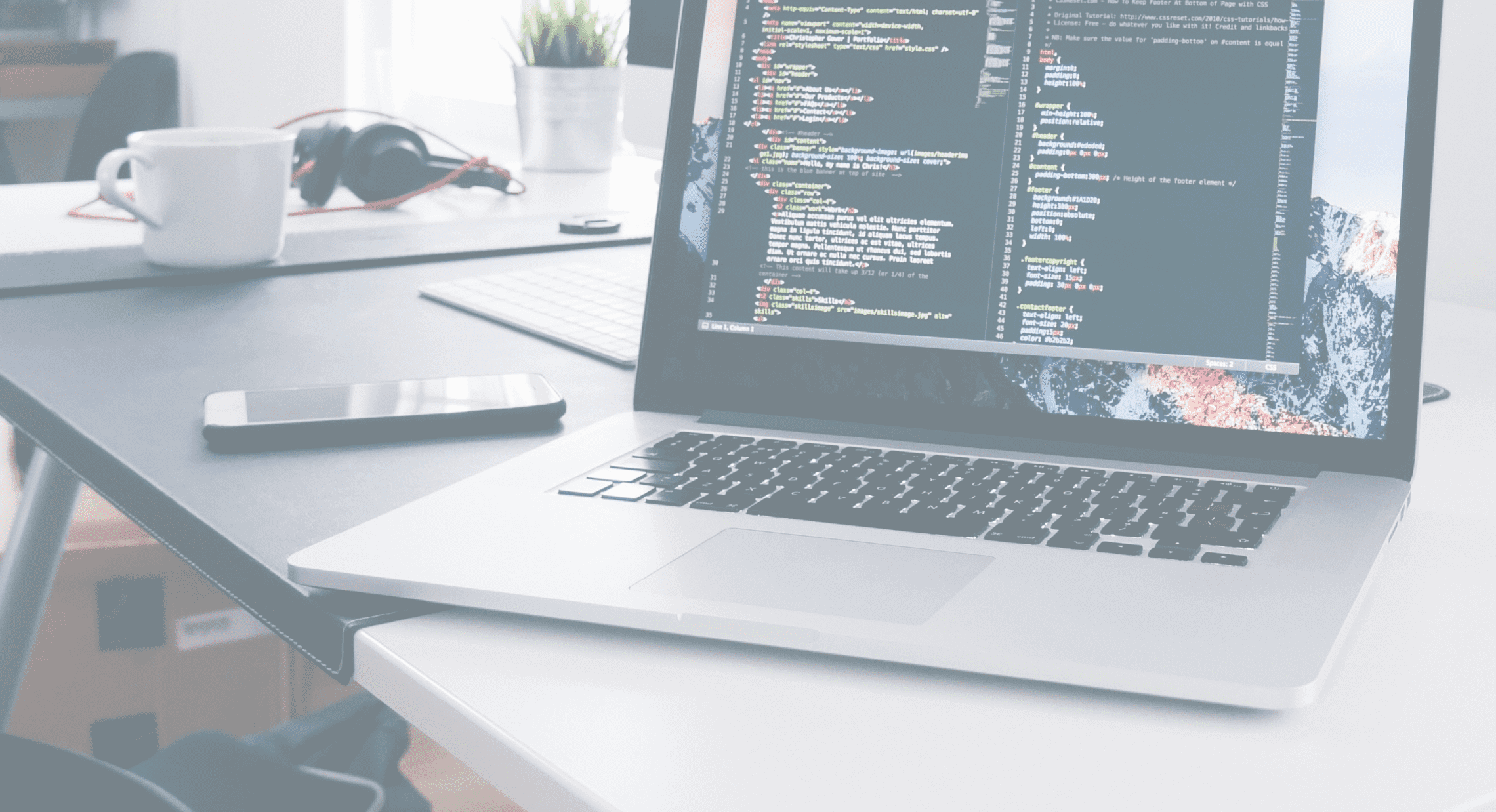 コードが表示されたノートパソコンのある作業机